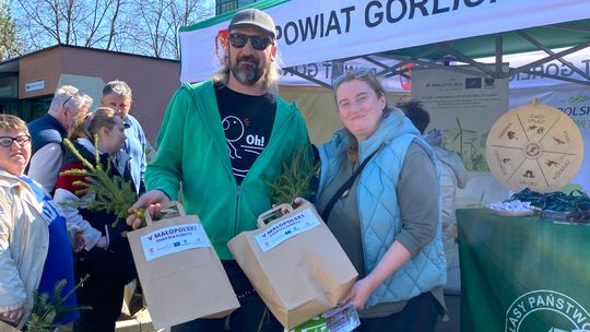 Zdjęcie przedstawia kobietę i mężczyznę trzymających papierową torbę z sadzonkami drzew