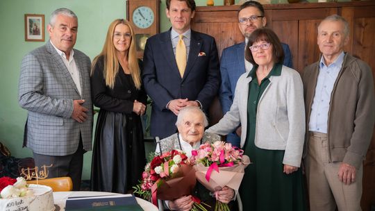 100. urodziny Stanisławy Gruszkowskiej z Gorlic. Wyjątkowy jubileusz w Sokole zdjęcie przedstawia grupę osób, kobieta siedzi na wózku inwalidzkim z kwiatami