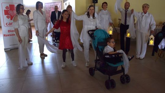 zdjęcie przedstawia grupę osób, które stoją z podniesionymi rękami trzymając białe chusty