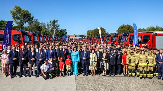 zdjęcie przedstawia dużą grupę ludzi między samochodami strażackimi