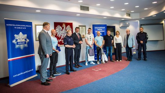 zdjęcie przedstawia kilka osób stojących pod ścianą w sali