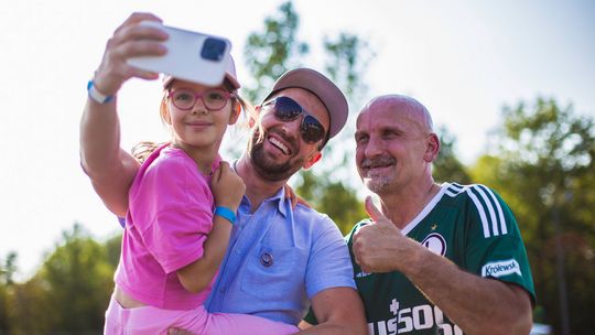 mężczyzna z dzieckiem na ręku robi sobie selfie z piłkarzem