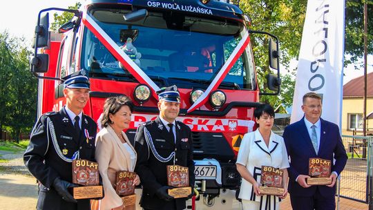 zdjęcie przedstawia kilka osób przed samochodem straży pożarnej