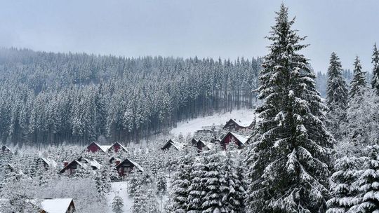 zdjęcie przedstawia zaśnieżone wzgórze z domami