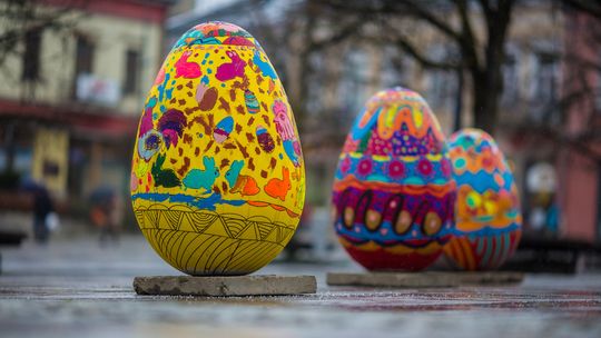 zdjęcie przedstawia pokolorowane makiety jajek ustawione na placu rynku w mieście