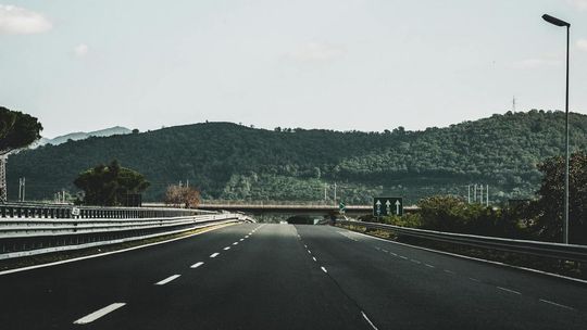 zdjęcie przedstawia autostradę, w dali wzniesienie obrośnięte lasem