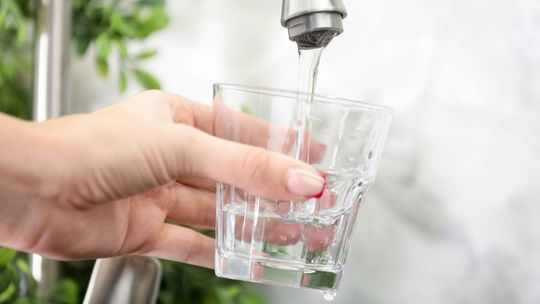 zdjęcie przedstawia dłoń ze szklanką wody