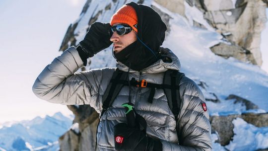 zdjęcie przedstawia mężczyznę w okularach i kurtce zimowej na tle gór