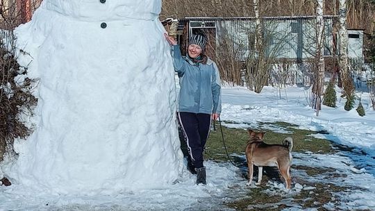 zdjęcie przedstawia kobietę z psem przy budowli bałwana