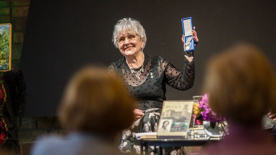 zdjęcie przedstawia kobietę trzymającą medal w dłoni