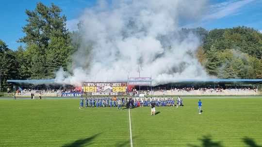 dym nad trybuną stadionu, drużyny na boisku przed meczem