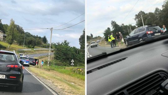 rozbity samochód stojący na poboczu, obok osoby i policjanci