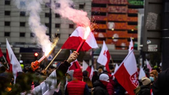 zdjęcie przedstawia tłum z racami i flagami