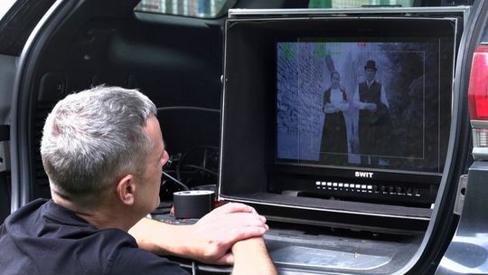Mężczyzna patrzący na ekran monitora, na nim podgląd z kadru filmu Weigl, Rafał Kukla z żoną