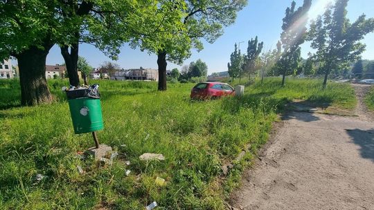 zdjęcie przedstawia czerwony samochód stojący w wysokiej trawie