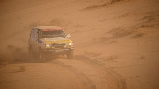 zdjęcie przedstawia samochód jadący po piasku pustyni