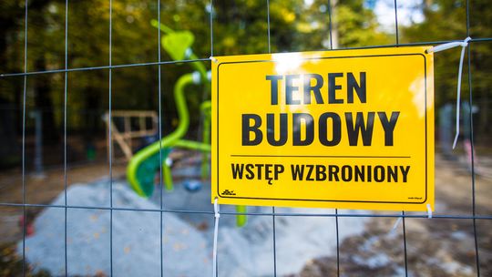 żółta tabliczka z napisem plac budowy powieszona na siatce w parku miejskim w Gorlicach