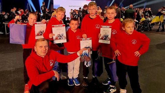 zdjęcie przedstawia dzieci i dorosłą osobę trzymającą medale i dyplomy