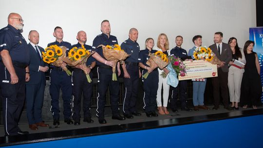 zdjęcie przedstawia policjantów z kwiatami na scenie