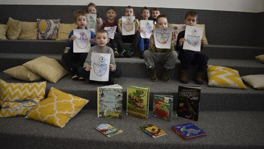 Dzieci z rysunkami i książkami w bibliotece