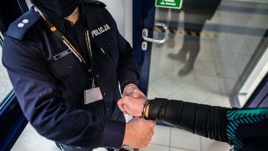 zdjęcie przedstawia policjanta zakładającego kajdanki na dłoń