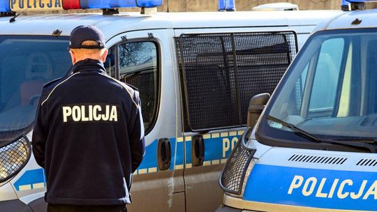 zdjęcie przedstawia policjanta stojącego przed radiowozami