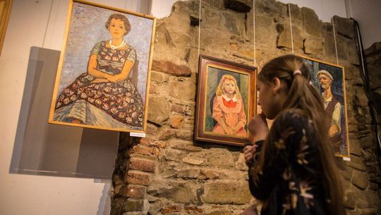 dziewczynka patrząca na namalowany portret wiszący na ścianie