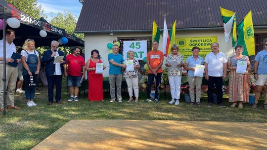 zdjęcie przedstawia grupę osób przed budynkiem na działce