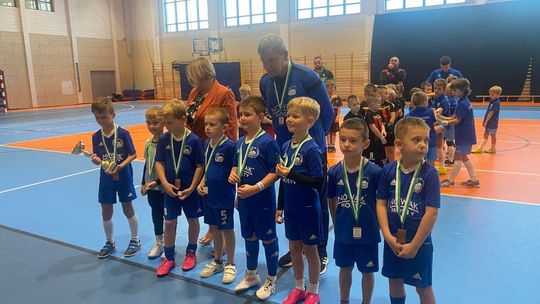 Zdjęcie przedstawia młodych piłkarzy z medalami w asyście trenera i poseł na Sejm
