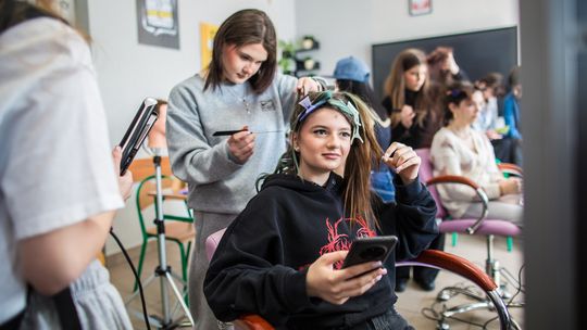 zdjęcie przedstawia dziewczynę, której fryzjerka robi włosy