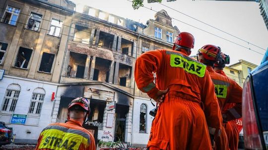 strażacy patrzący na spalone mury kamienicy w Poznaniu