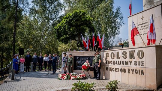 zdjęcie przedstawia grupę osób pod pomnikiem