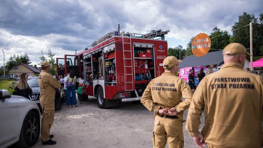 zdjęcie przedstawia samochód strażacki i grupę dzieci i strażaków koło niego