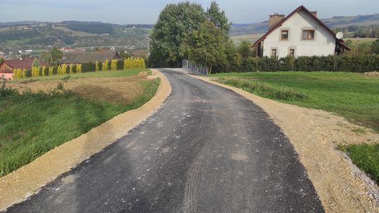 Fragment asfaltowej drogi w Gminie Bobowa, w tle domy mieszkalne