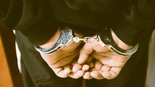 Zdjęcie przedstawia dłonie zakute w kajdanki