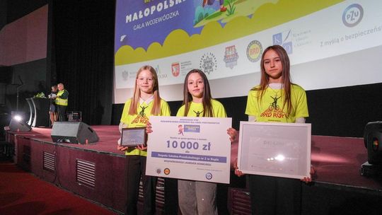 Zdjęcie przedstawia dzieci trzymające bon z nagrodą pieniężną