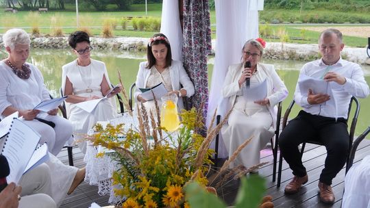 zdjęcie przedstawia osoby siedzące obok siebie na krzesełkach trzymające książki przed sobą