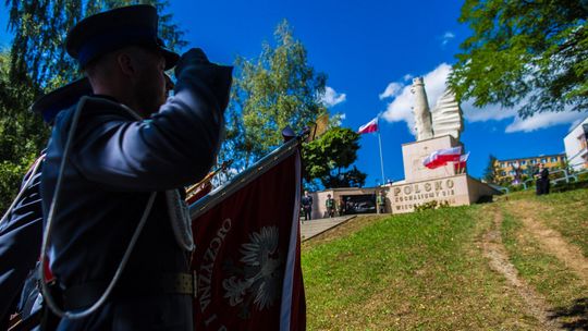 policjant salutujący przed pomnikiem