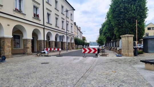 zdjęcie przedstawia ulicę w mieście, stoją przy niej barierki biało-czerwone