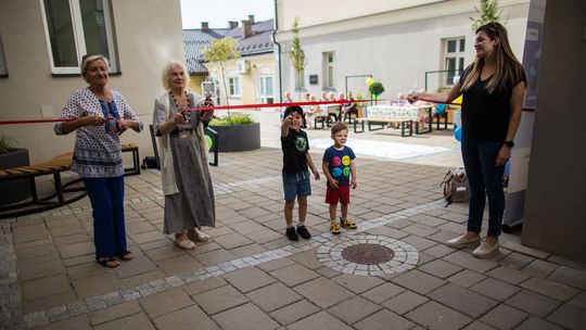 zdjęcie przedstawia trzy osoby przecinające wstęgę podczas otwarcia zielonego dziedzińca