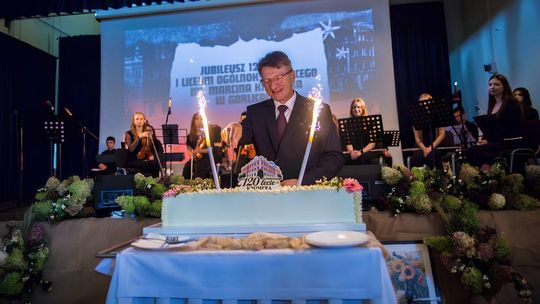 mężczyzna pod krawatem w garniturze krojący tort