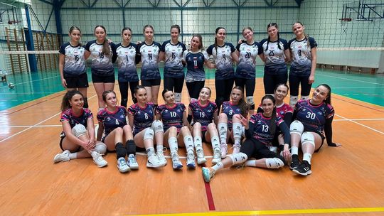 zdjęcie przedstawia młode dziewczyny w koszulkach sportowych siedzące i stojące na parkiecie po meczu siatkówki