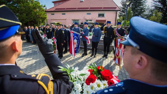 policjanci trzymający sztandar i salutujący podczas śpiewania hymnu