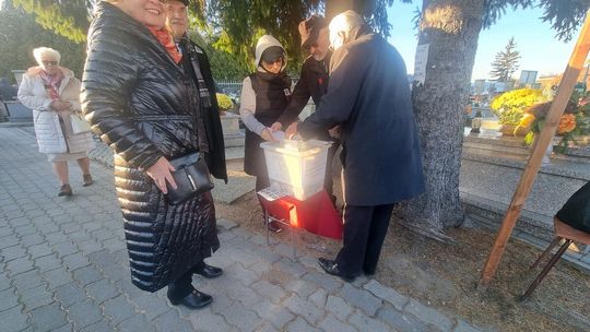 Gorliczanie wsparli ratowanie zabytków cmentarza. Na co pójdą zebrane środki? zdjęcie przedstawia kilka osób wokół plastikowego pudełka na datki na ratowanie cmentarnych zabytków