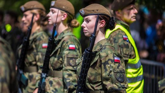 zdjęcie przedstawia kobiety z karabinami w strojach wojskowych