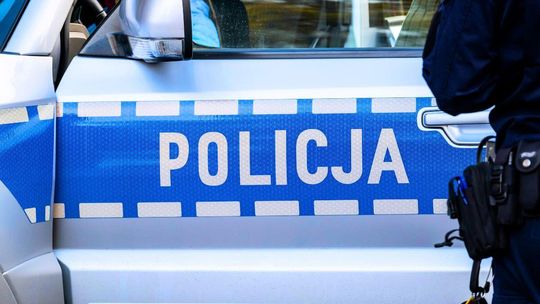 zdjęcie przedstawia policjanta stojącego przed radiowozem