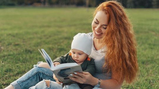 Kobieta z dzieckiem na rękach czytają książkę