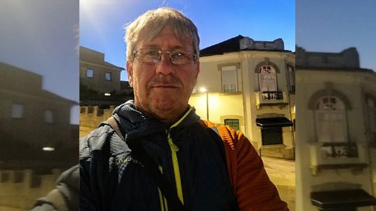 portret mężczyzny w okularach, w tle domy