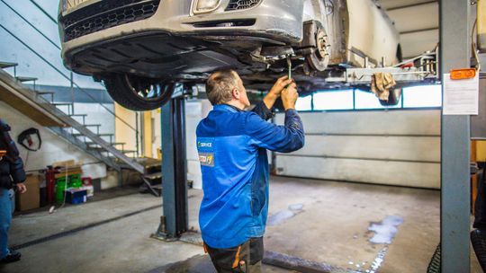 Zdjęcie przedstawia kobietę przed ladą w olejami silnikowymi