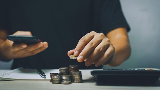 zdjęcie przedstawia mężczyznę trzymającego bilon i kalulator